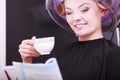 Girl reading magazine drinking coffee. Hairdryer in hair beauty salon Royalty Free Stock Photo