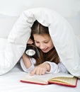 Girl reading under blanket