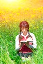 Girl reads book sitting in a meadow Royalty Free Stock Photo