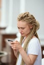 Girl reads on phone, pensive look, hair braided in dreadlocks Royalty Free Stock Photo