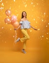 Girl ready for a party with balloon. Joyful an happiness expression. Yellow background