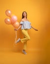 Girl ready for a party with balloon. Joyful an happiness expression. Yellow background