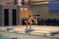 Girl ready to jump into indoor sport swimming pool. standing on arms with legs up