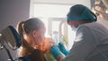 Little girl on reception at the dentist, the stomatologist cleaning and watering the child`s teeth, girl smiling