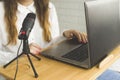 A blogger records a podcast into a microphone in a home interior.