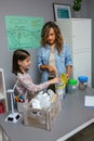 Girl recycling plastic pack with her teacher in an ecology classroom