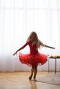 Girl in red ball gown, dancing in room on floo