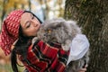 A girl in a red bandana on her head holds a British cat in her arms against the background of yellow autumn maple leaves. Royalty Free Stock Photo