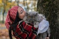 A girl in a red bandana on her head holds a British cat in her arms against the background of yellow autumn maple leaves Royalty Free Stock Photo