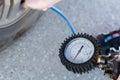 A girl with a red bauble on her hand pumps up tires with a compressor for pumping tires at a gasoline Royalty Free Stock Photo