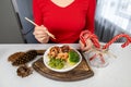 A girl in a red blouse and brown apron holds a plate of golden rice, king prawns, green beans and broccoli in her hands