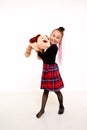Girl in in a red checked skirt and with toy dog in the studio with white background during photo shoot. Cute young Royalty Free Stock Photo