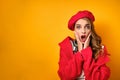 A girl in a red coat and beret is looks in shock at the frame, opening her mouth and pressing her hands to her face. Royalty Free Stock Photo