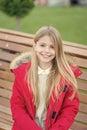 Girl in red coat sit on bench in park Royalty Free Stock Photo