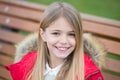 Girl in red coat sit on bench in park Royalty Free Stock Photo