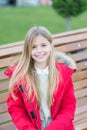 Girl in red coat sit on bench in park Royalty Free Stock Photo