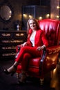 Girl in red costume sitting in red chair in the dark room Royalty Free Stock Photo