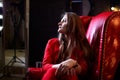 Girl in red costume sitting in red chair in the dark room Royalty Free Stock Photo