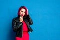 Girl with red hair makes a show with big soap bubbles or posing on a blue wall background Royalty Free Stock Photo