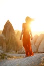 Girl in a red dress barefoot among the rocks at sunrise. Cappadocia. Turkey.