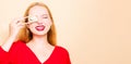 Girl in a red dress on a beige background. A woman eats with chopsticks for sushi, closes her eyes with them and grimaces, smiles Royalty Free Stock Photo