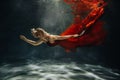 A girl in a red dress is floating under the water with a suitcase.Journey under the water of a single woman.The concept of Royalty Free Stock Photo