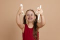 Girl in red dress hold flute disassembled in parts over head and gloat, beige background. Learning to play woodwind