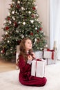 Girl in red dress laughs and enjoys gift. Little girl opening magical christmas present at home. child holds christmas present. Me