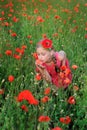 Girl in a red dress on the poppy field smelling a flowers Royalty Free Stock Photo