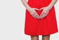 Girl in the red dress pressed her hands to the stomach, heart gesture, love. Women`s health, sexuality