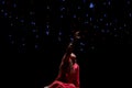 Girl in a red dress reaching to the stars in the darkness in Alif Pavilion of Expo 2020 in Dubai