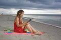 Girl with red dress reading a book in the beach