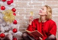 Girl in red dress relaxing with glass of champagne near christmas tree. Woman happy drink alcohol near christmas tree Royalty Free Stock Photo