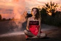 Girl in red dress on the road and white flour cloud behind her in the evening at sunset Royalty Free Stock Photo