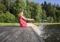 girl in a red dress sitting on a wooden pier Royalty Free Stock Photo