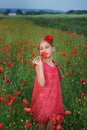 Girl in red dress walks at poppy field Royalty Free Stock Photo