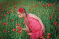 Girl in red dress walks at poppy field Royalty Free Stock Photo