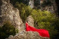 A girl in a red dress waving in the wind on the ruins of an ancient antique city in the mountains.