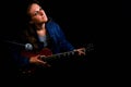 A girl with a red electric guitar records a song at the recording Studio, copy space. Female guitarist in denim jacket on black Royalty Free Stock Photo