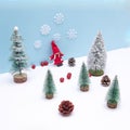 A girl in red in an evergreen forest on the snow with a blue background. Cones scattered on the snow. Minimalistic look