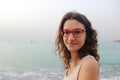 Girl in red glasses on the coast on a cloudy day Vacation by the sea. Summer, outdoors. Beach landscape Royalty Free Stock Photo