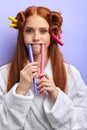 Girl with red hair in hair curlers isolated in purple background Royalty Free Stock Photo