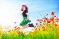Girl with red hair jumping in poppy field over blue sky Royalty Free Stock Photo