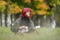 A girl with red hair plays a white ukulele.