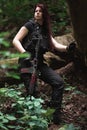 Girl with red hair and a rifle in a dense forest