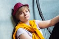 Girl with a red hat sits near a wall