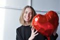 a girl with red heart-shaped balloons smiles and enjoys life. Caucasian woman celebrating valentine& x27;s day. A note to Royalty Free Stock Photo