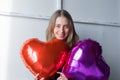 a girl with red heart-shaped balloons smiles and enjoys life. Caucasian woman celebrating valentine& x27;s day. A note to Royalty Free Stock Photo