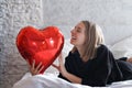 a girl with red heart-shaped balloons smiles and enjoys life. Caucasian woman celebrating valentine& x27;s day. A note to Royalty Free Stock Photo