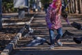 Girl in a red jacket, hat and glasses chasing pigeons in the park Royalty Free Stock Photo